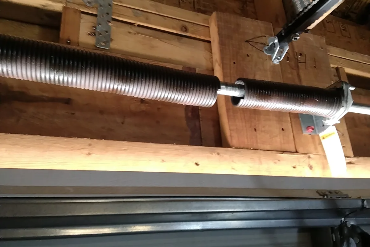 Broken garage door torsion spring with a visible gap in the coil, found on a Reliable Garage Doors service call