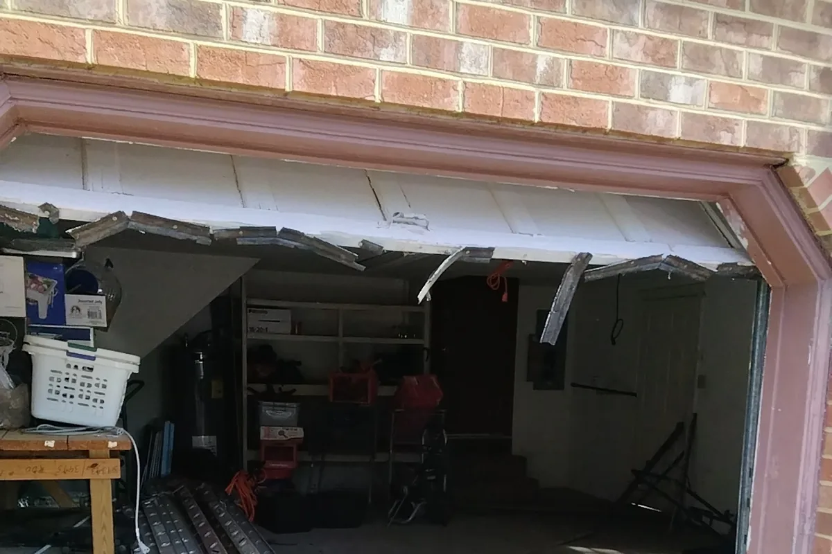 Garage door hanging crooked with a buckled top panel after coming off its tracks, a call-right-away situation
