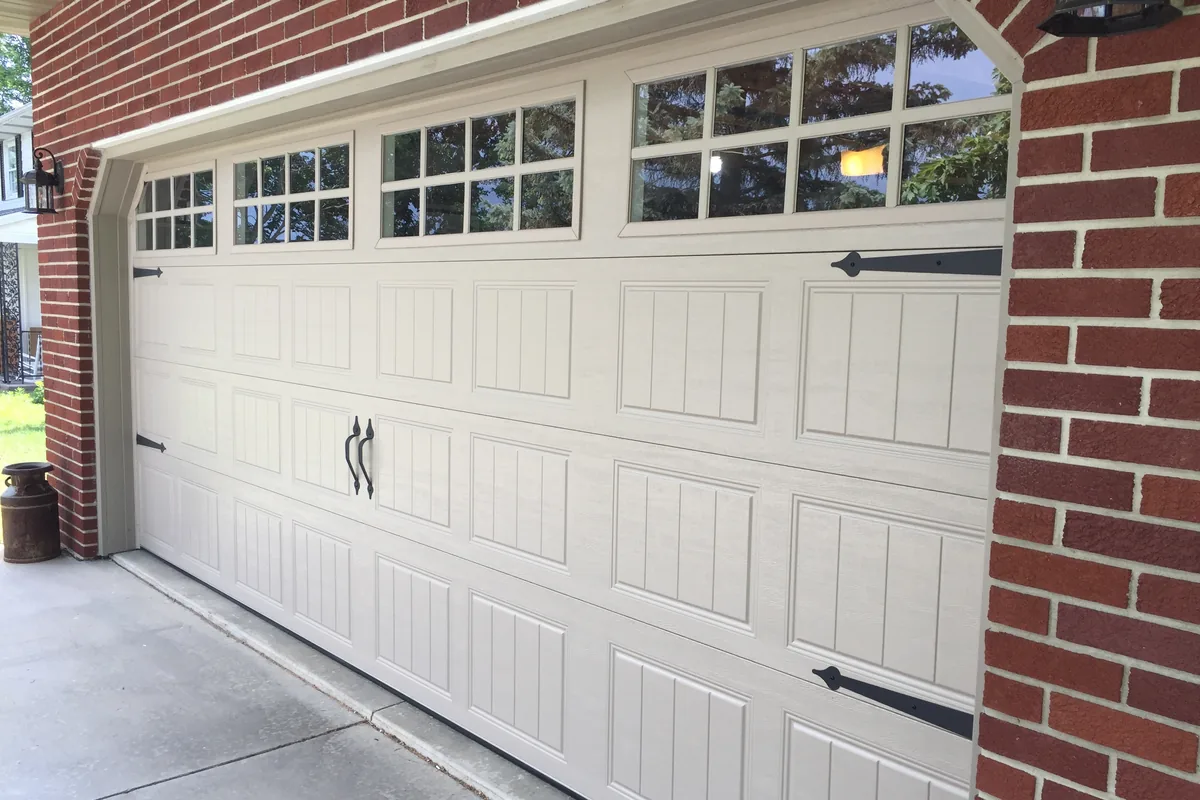 Carriage-style garage door with windows on a brick home in Hampton Roads, serviced by Reliable Garage Doors